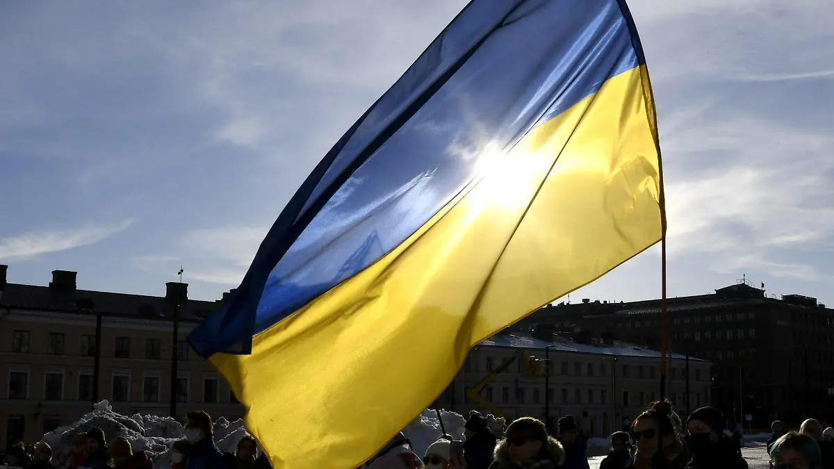 27.02.2022, Finnland, Helsinki: Teilnehmer einer Demonstration halten eine ukrainische Fahne bei einem Protest gegen die Invasion in die Ukraine. Russlands Nachbar Finnland will seine militärische Abwehr wegen der Entwicklungen in der Ukraine mit Waffensystemen aus Israel stärken. Foto: Jussi Nukari/Lehtikuva/dpa +++ dpa-Bildfunk +++