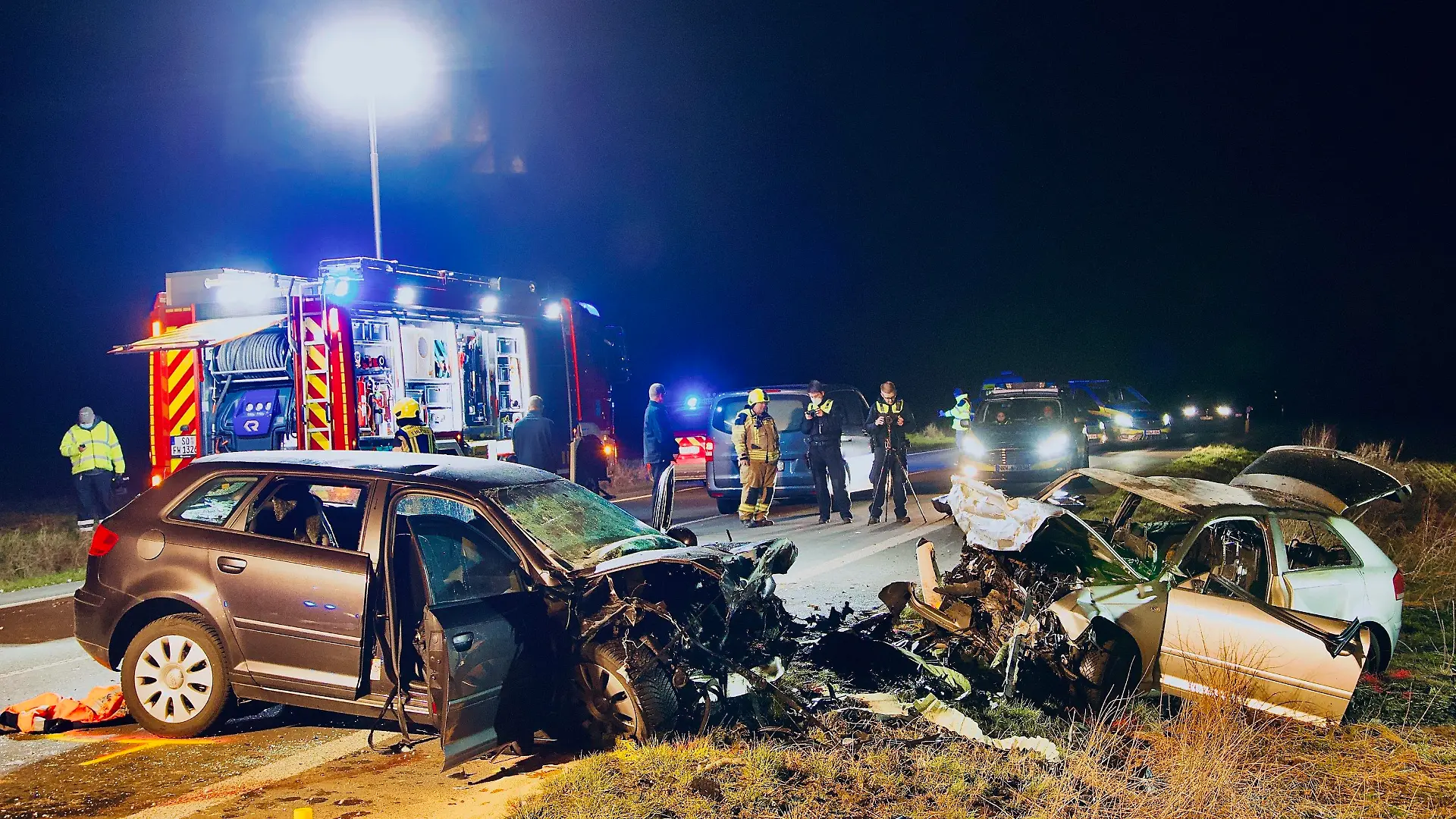 05.03.2022, Nordrhein-Westfalen, Unna: Einsatzkräfte der Polizei und Feuerwehr stehen an der Unfallstelle. Bei einem Frontalzusammenstoß in Unna sind am Samstag drei Menschen gestorben. Foto: Andreas Dunker/dpa +++ dpa-Bildfunk +++