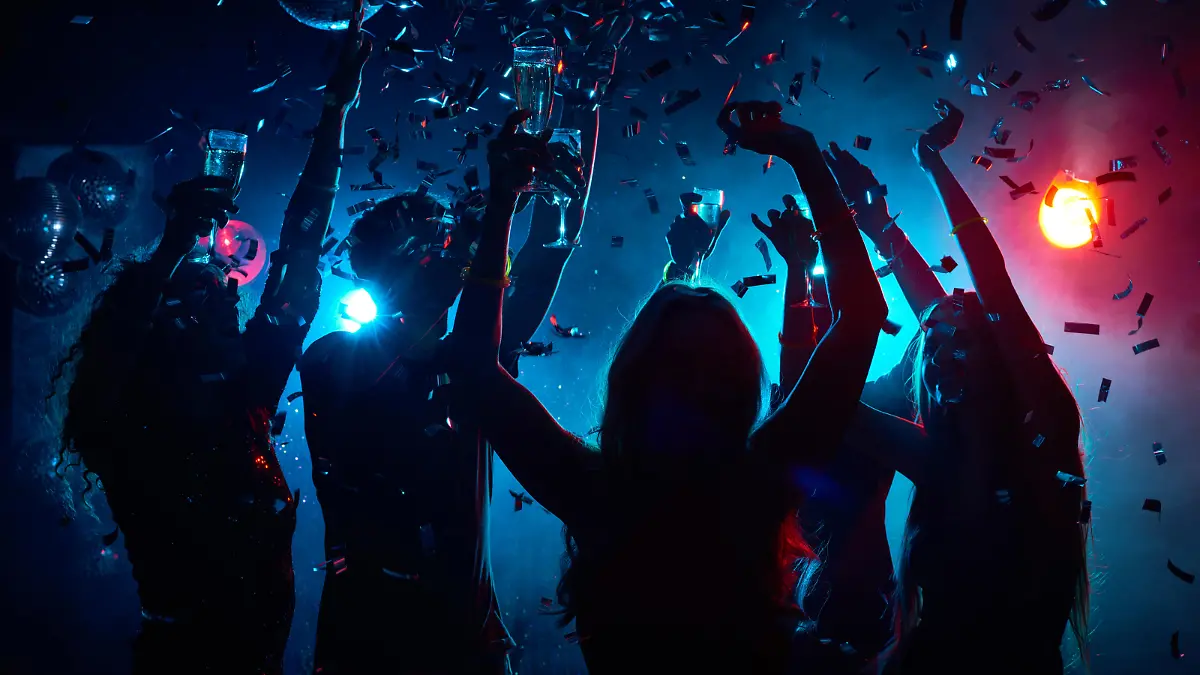 Silhouette of young people with raised flutes having fun and clubbing