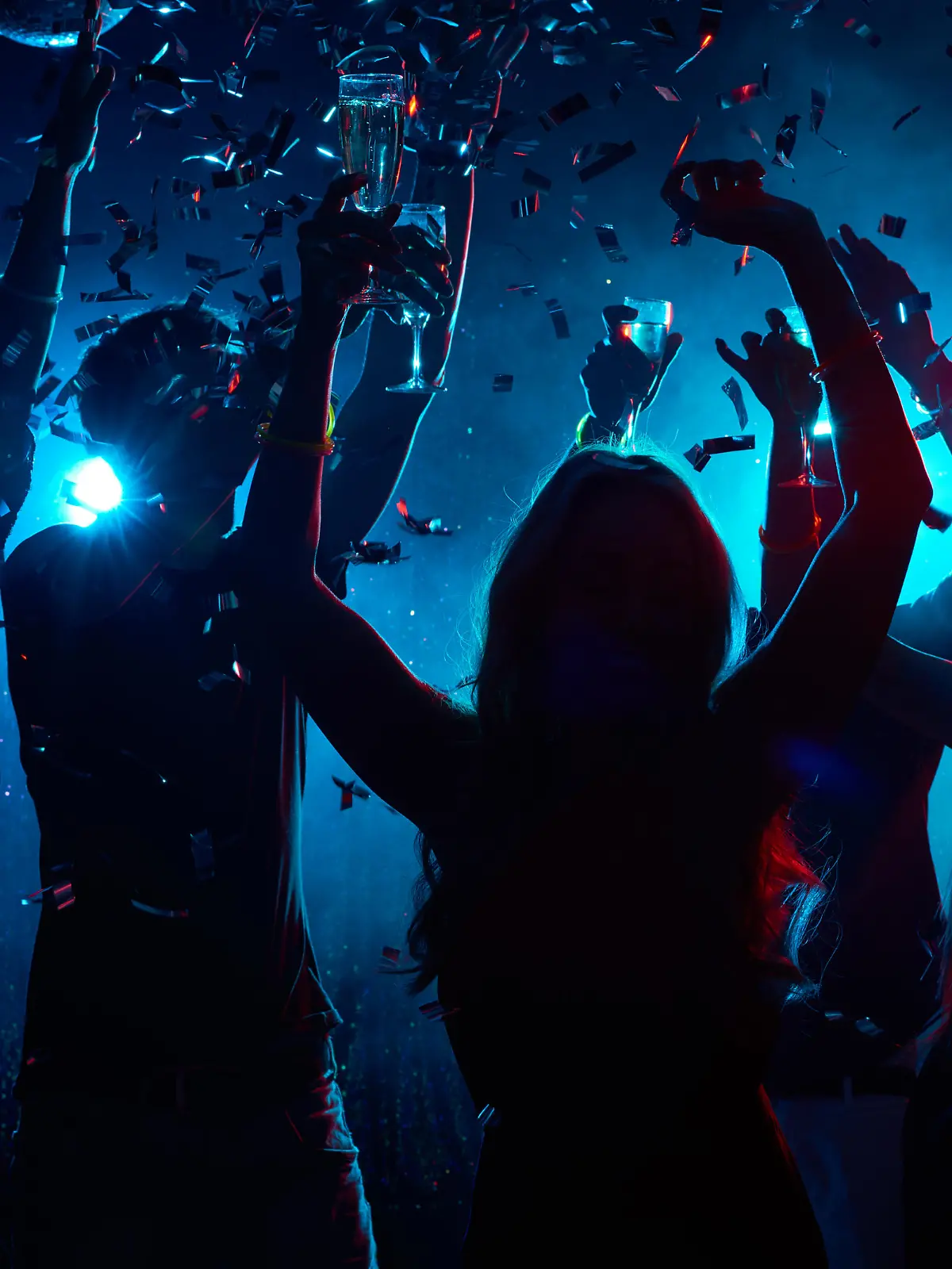 Silhouette of young people with raised flutes having fun and clubbing