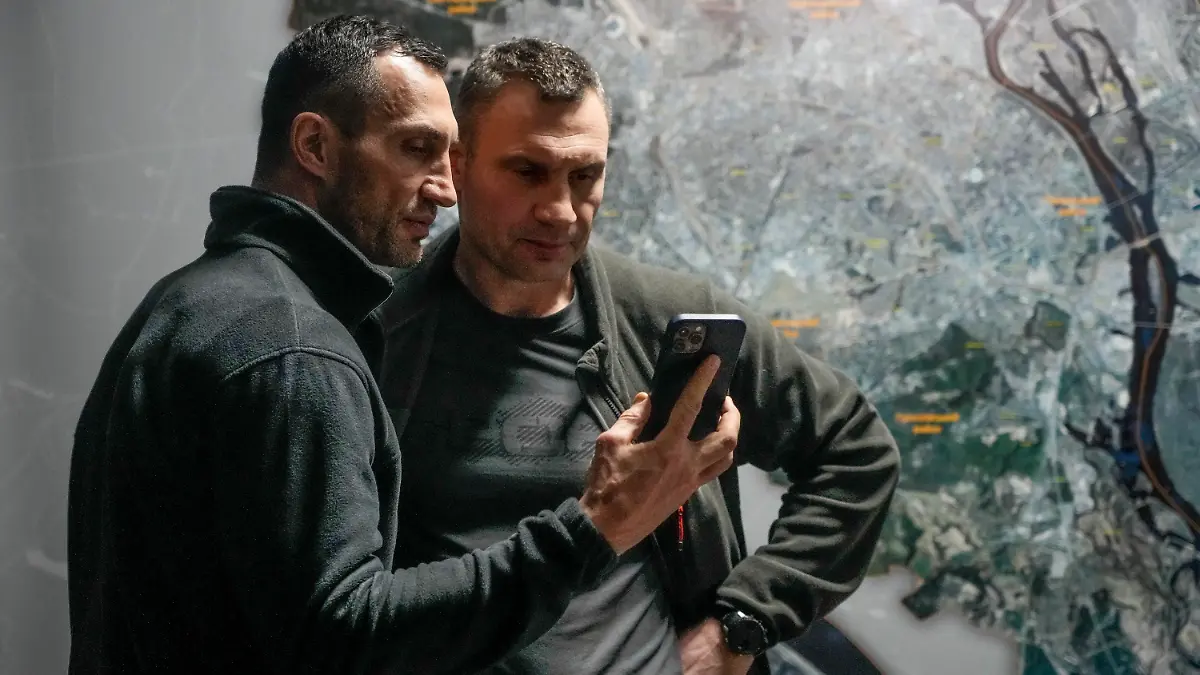 dpatopbilder - 27.02.2022, Ukraine, Kiew: Vitali Klitschko (r), Bürgermeister von Kiew und ehemaliger Box-Profi, und sein Bruder Wladimir Klitschko, ebenfalls ehemaliger Box-Profi, schauen auf ein Smartphone im Rathaus in Kiew. Russische Truppen haben den erwarteten Angriff auf die Ukraine gestartet und drangen in die Hauptstadt vor. Foto: Efrem Lukatsky/AP/dpa +++ dpa-Bildfunk +++