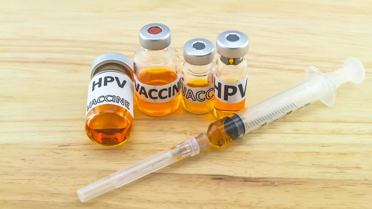 Bottle vaccine of Human papillomavirus (HPV) vaccine and disposable syringe on wooden background