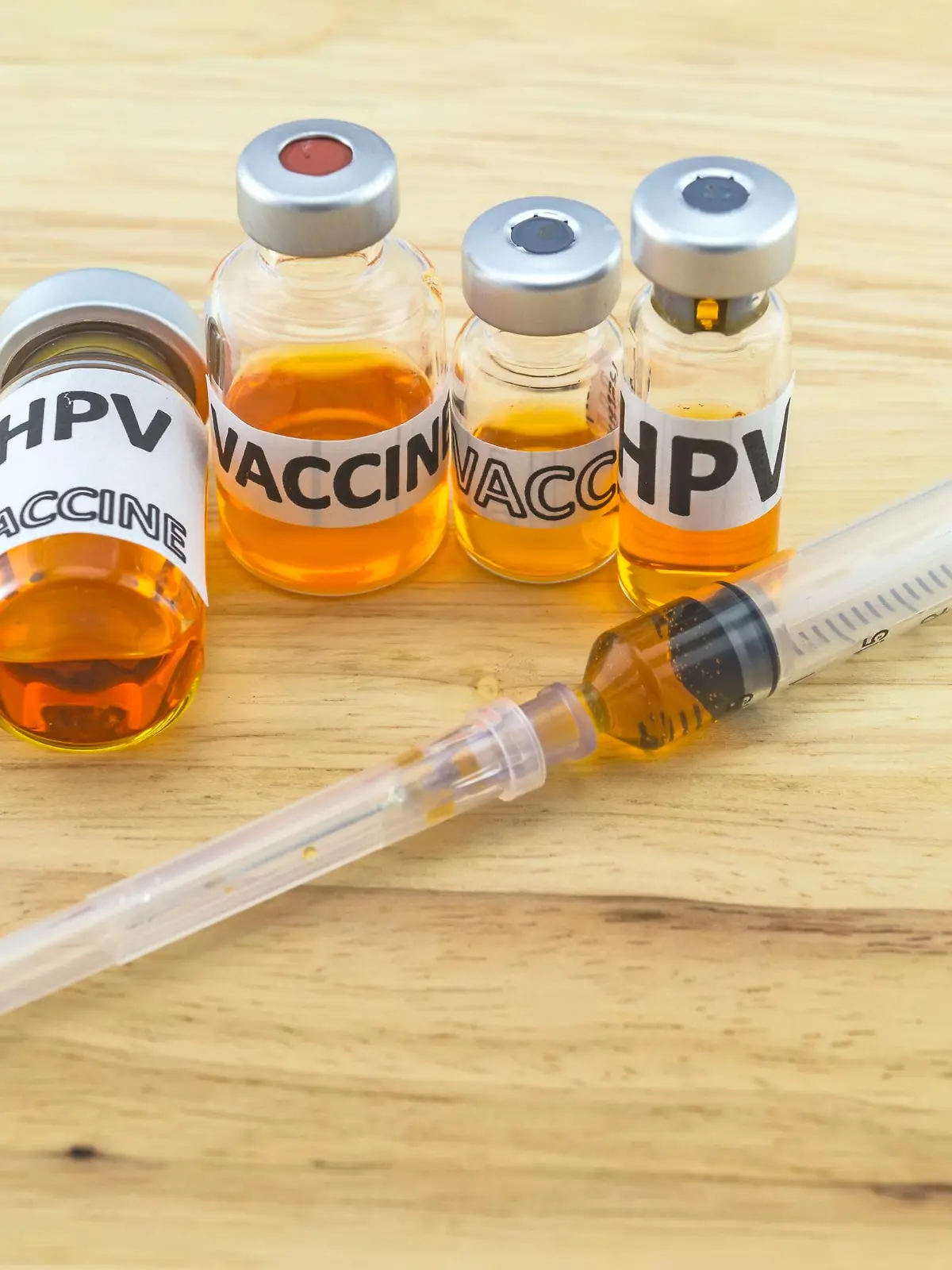 Bottle vaccine of Human papillomavirus (HPV) vaccine and disposable syringe on wooden background