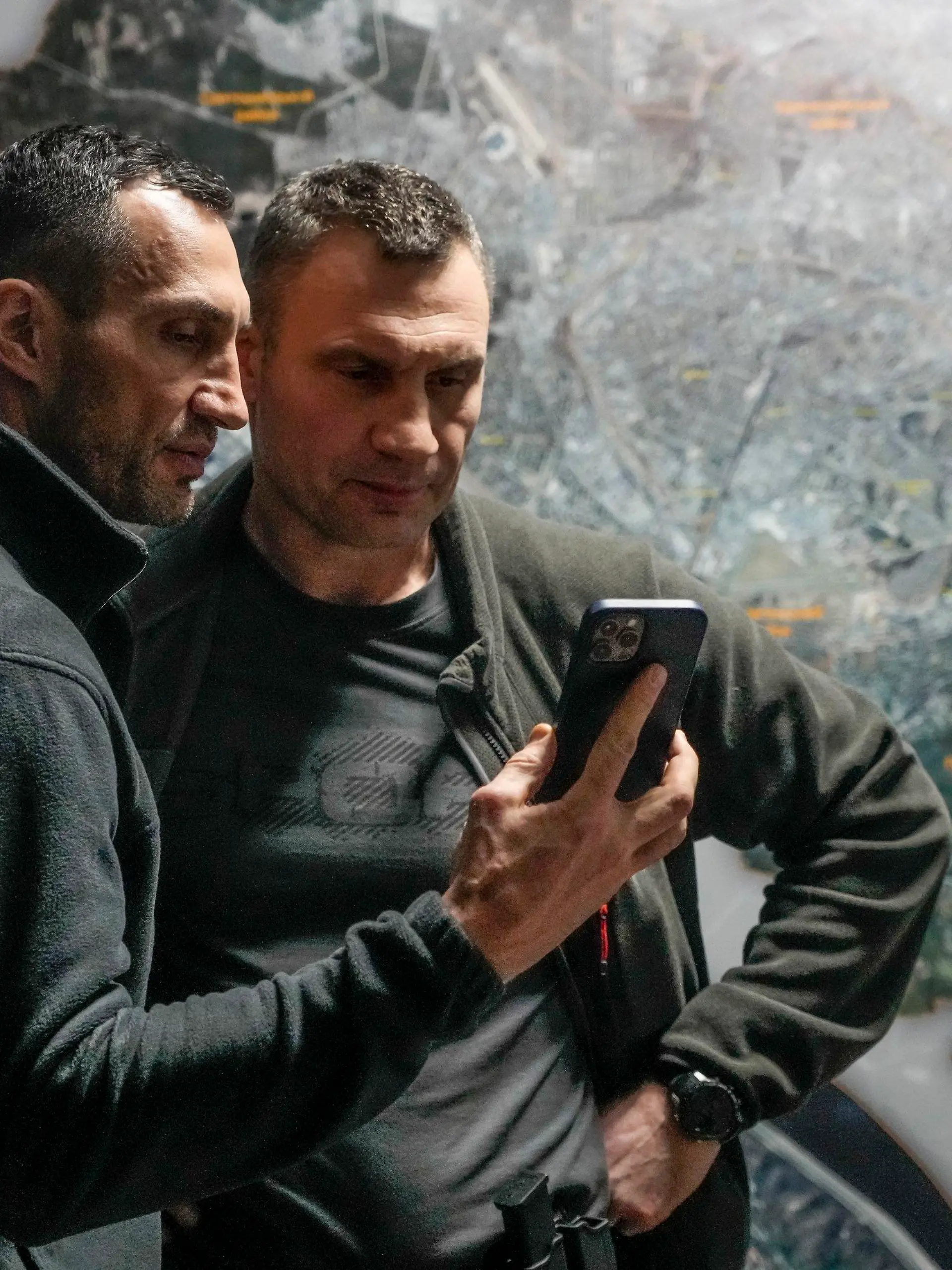 27.02.2022, Ukraine, Kiew: Vitali Klitschko (r), Bürgermeister von Kiew und ehemaliger Box-Profi, und sein Bruder Wladimir Klitschko, ebenfalls ehemaliger Box-Profi, schauen auf ein Smartphone im Rathaus in Kiew. Russische Truppen haben den erwarteten Angriff auf die Ukraine gestartet und drangen in die Hauptstadt vor. Foto: Efrem Lukatsky/AP/dpa +++ dpa-Bildfunk +++