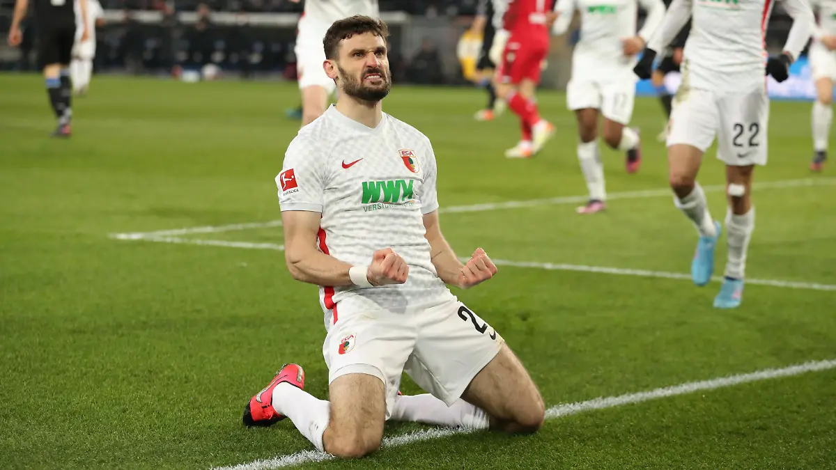Fußball: Bundesliga, Arminia Bielefeld - FC Augsburg, 25. Spieltag in der Schüco-Arena. Augsburgs Torschütze Daniel Caligiuri (M, unten) feiert seinen Treffer zum 0:1.