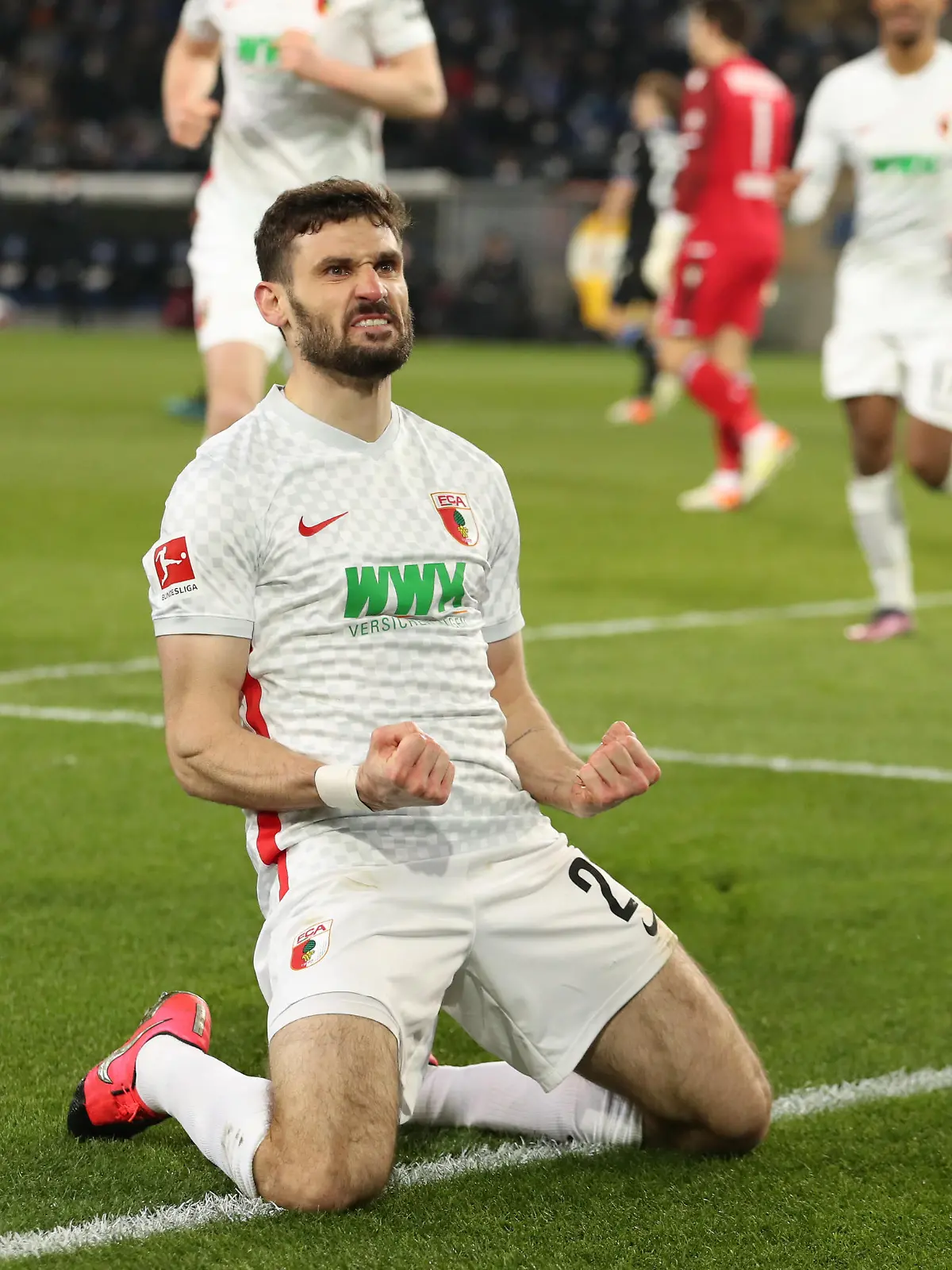 Fußball: Bundesliga, Arminia Bielefeld - FC Augsburg, 25. Spieltag in der Schüco-Arena. Augsburgs Torschütze Daniel Caligiuri (M, unten) feiert seinen Treffer zum 0:1.