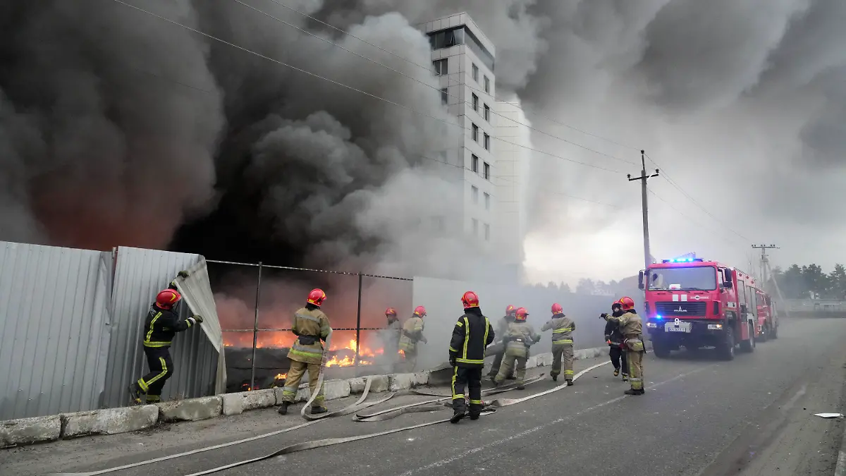 03.03.2022, Ukraine, Kiew: Einsatzkräfte der Feuerwehr stehen vor einem Logistikzentrum, dass nach Beschuss in Brand geraten ist. Russland hat seine Angriffe auf belebte Städte ausgeweitet, was von Präsident Selenskyj als Terrorkampagne bezeichnet wurde. Foto: Efrem Lukatsky/AP/dpa +++ dpa-Bildfunk +++