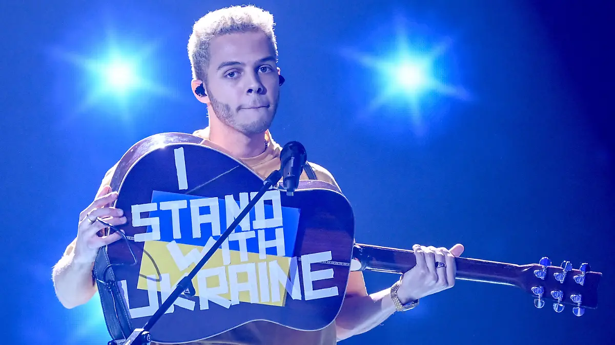 04.03.2022, Berlin: Malik Harris steht bei der Show "Germany 12 Points - der deutsche ESC-Vorentscheid" auf der Bühne und zeigt seine Gitarre, auf der "I stand with Ukraine" steht. Bei der Live-Übertragung stellen die Kandidatinnen und Kandidaten ihre Songs vor. Am Ende steht fest, wer Deutschland beim Eurovision Song Contest (ESC) in Turin am 14. Mai vertritt. Foto: Britta Pedersen/dpa-POOL/dpa +++ dpa-Bildfunk +++