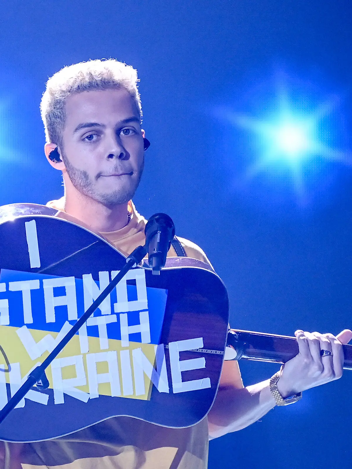 04.03.2022, Berlin: Malik Harris steht bei der Show "Germany 12 Points - der deutsche ESC-Vorentscheid" auf der Bühne und zeigt seine Gitarre, auf der "I stand with Ukraine" steht. Bei der Live-Übertragung stellen die Kandidatinnen und Kandidaten ihre Songs vor. Am Ende steht fest, wer Deutschland beim Eurovision Song Contest (ESC) in Turin am 14. Mai vertritt. Foto: Britta Pedersen/dpa-POOL/dpa +++ dpa-Bildfunk +++