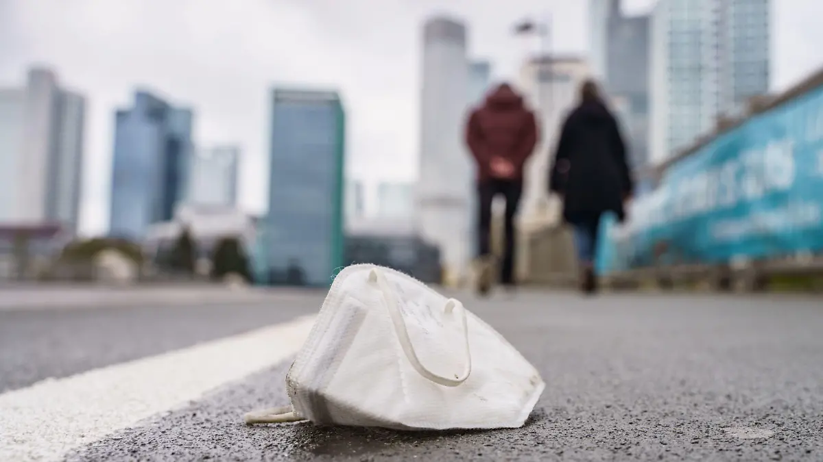 ARCHIV - 18.04.2021, Hessen, Frankfurt/Main: Eine FFP2-Maske liegt auf dem nassen Gehweg der Untermainbrücke, die in die Innenstadt und das Bankenviertel führt. (zu dpa "Corona-Kabinett berät über geplante Lockerungen der Corona-Regeln»") Foto: Frank Rumpenhorst/dpa +++ dpa-Bildfunk +++