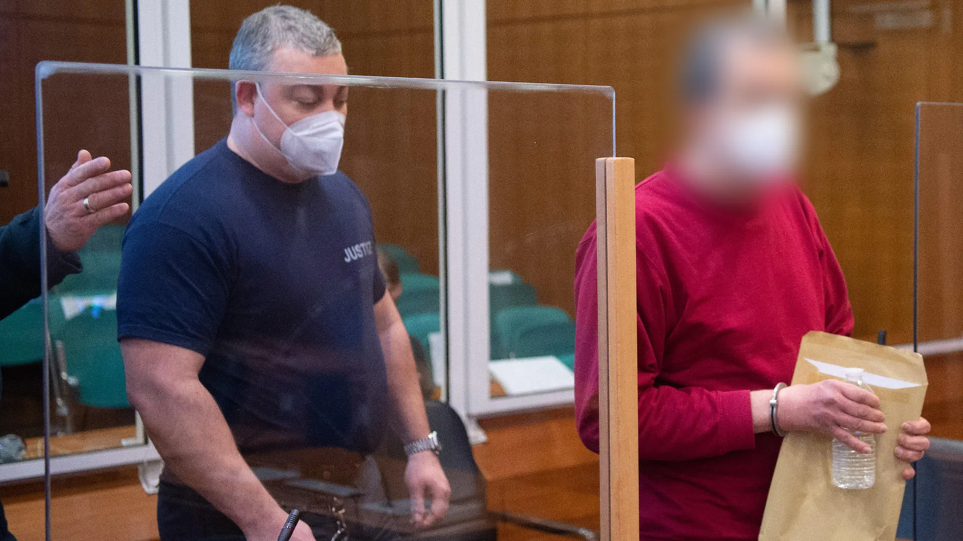 24.02.2022, Hessen, Frankfurt/Main: Der Angeklagte und mutmaßliche Verfasser der ·NSU 2.0·-Drohschreiben wird mit Handschellen in den Verhandlungssaal geführt. Dem Berliner werden unter anderem Beleidigung, versuchte Nötigung und Bedrohung vorgeworfen. Empfänger der Drohschreiben waren Privatpersonen, Personen des öffentlichen Lebens sowie Behörden und Institutionen. Die Schreiben enthielten massive verbale Beleidigungen und Todesdrohungen. Foto: Boris Roessler/dpa-Pool/dpa - ACHTUNG: Person(en) wurde(n) aus rechtlichen Gründen gepixelt +++ dpa-Bildfunk +++