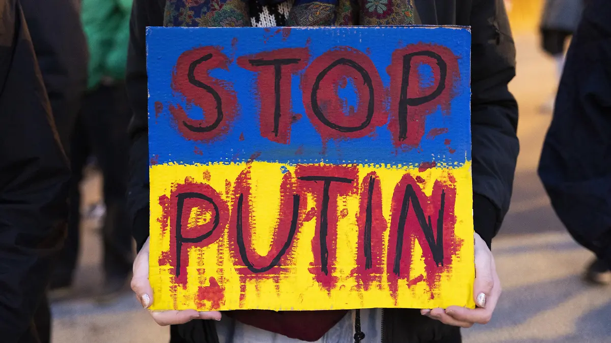 03.03.2022, Schweiz, Bern: Ein Demonstrierender hält ein Schild mit der Aufschrift «Stop Putin» während eines Protests gegen die russische Invasion in die Ukraine hoch. Foto: Peter Klaunzer/KEYSTONE/dpa +++ dpa-Bildfunk +++