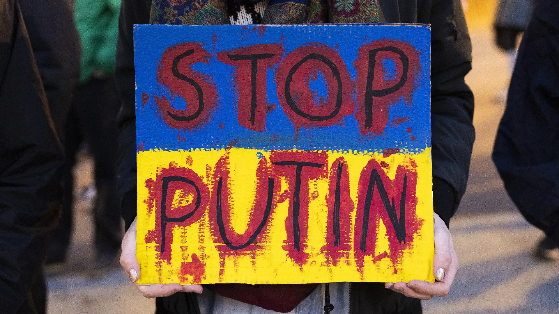 03.03.2022, Schweiz, Bern: Ein Demonstrierender hält ein Schild mit der Aufschrift «Stop Putin» während eines Protests gegen die russische Invasion in die Ukraine hoch. Foto: Peter Klaunzer/KEYSTONE/dpa +++ dpa-Bildfunk +++
