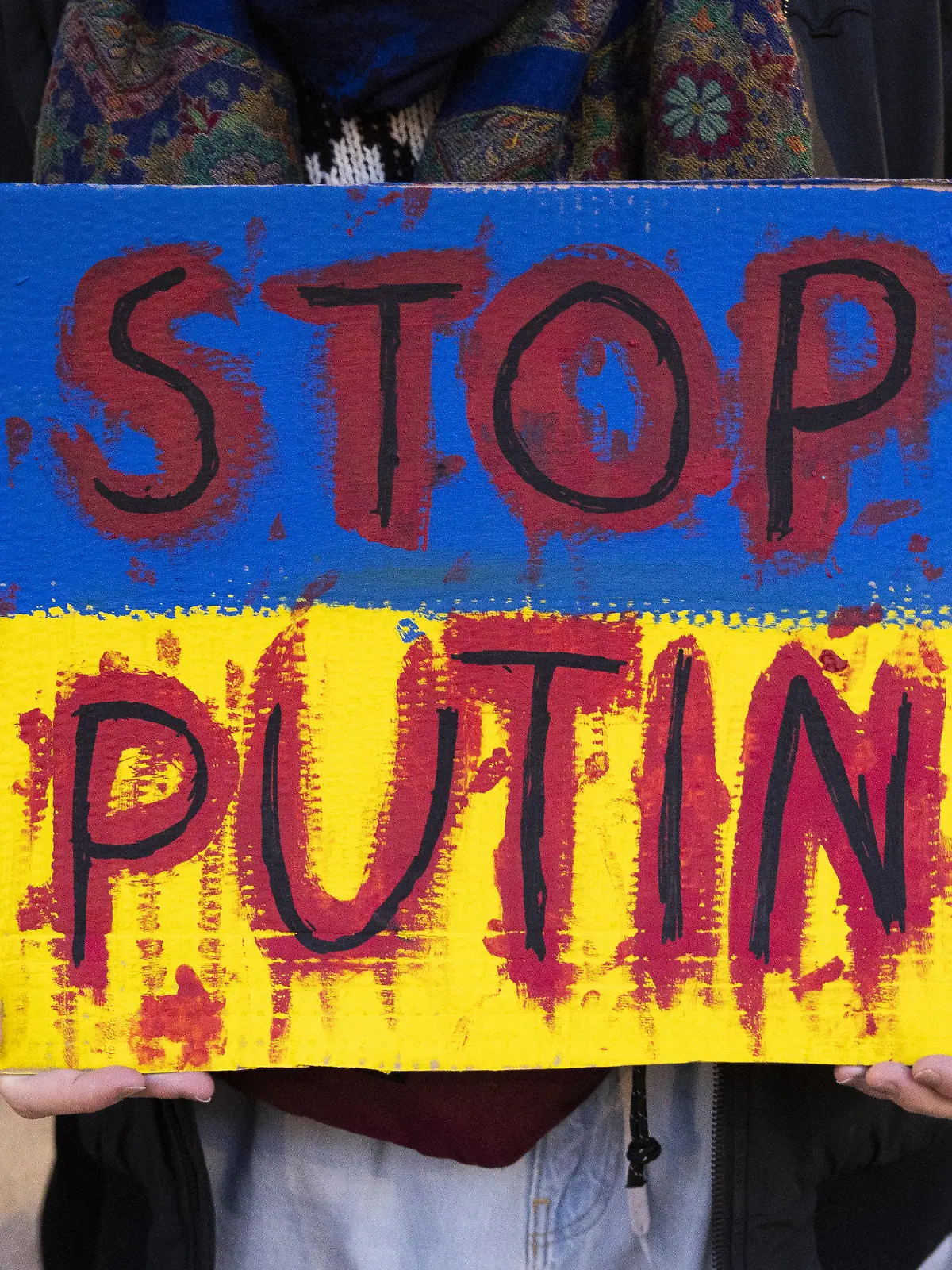 03.03.2022, Schweiz, Bern: Ein Demonstrierender hält ein Schild mit der Aufschrift «Stop Putin» während eines Protests gegen die russische Invasion in die Ukraine hoch. Foto: Peter Klaunzer/KEYSTONE/dpa +++ dpa-Bildfunk +++