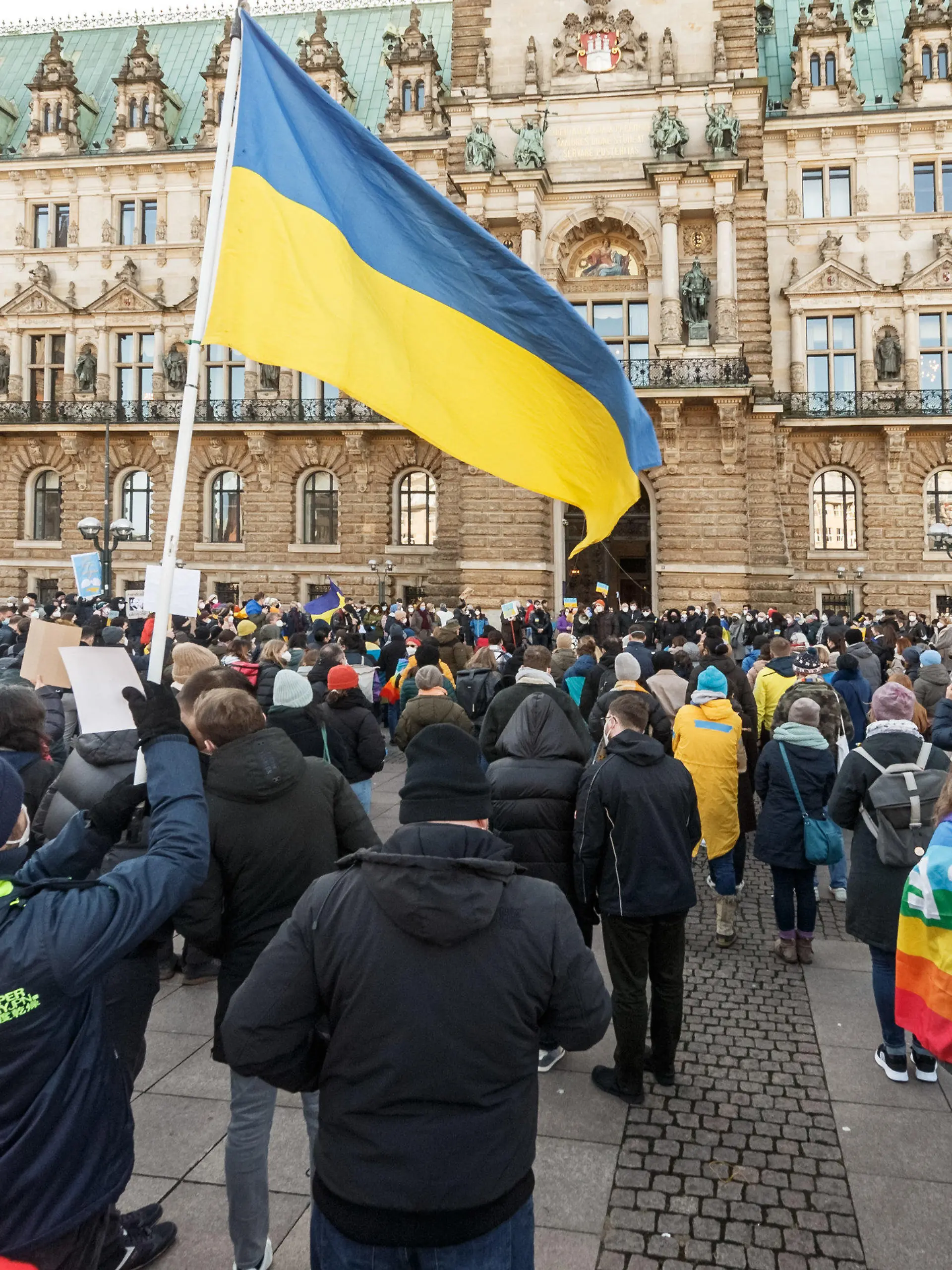 27.02.2022, Hamburg: Ein Kundgebungsteilnehmer hält eine ukrainische Fahne bei einer Demonstration auf dem Rathausmarkt gegen den russischen Angriff auf die Ukraine. Foto: Markus Scholz/dpa +++ dpa-Bildfunk +++