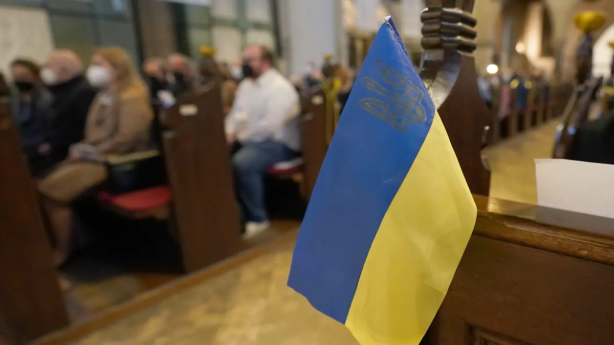 26.02.2022, Hamburg: Eine kleine Ukraine-Flagge hängt während eines Gedenkgottesdienstes für die Ukraine in einer Sitzreihe der Hauptkirche St. Petri. In Hamburg sind am Samstag wieder zahlreiche Menschen gegen den Krieg in der Ukraine auf die Straße gegangen. Foto: Marcus Brandt/dpa +++ dpa-Bildfunk +++