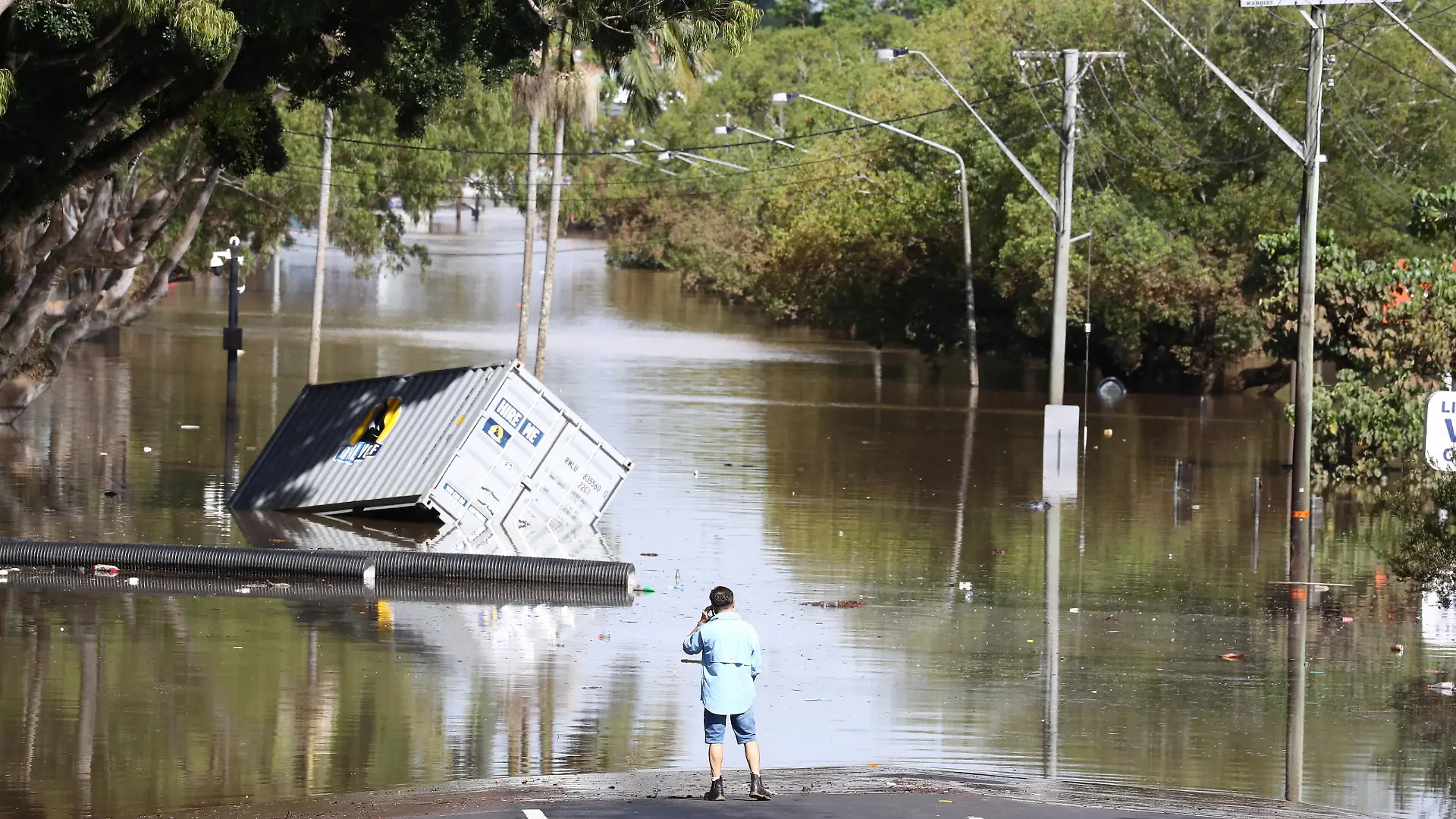 A man stands in front of a flooded street following heavy rains in Lismore, New South Wales, Australia March 2, 2022. AAP Image/Jason O'Brien via REUTERS ATTENTION EDITORS - THIS IMAGE WAS PROVIDED BY A THIRD PARTY. NO RESALES. NO ARCHIVE. AUSTRALIA OUT. NEW ZEALAND OUT.