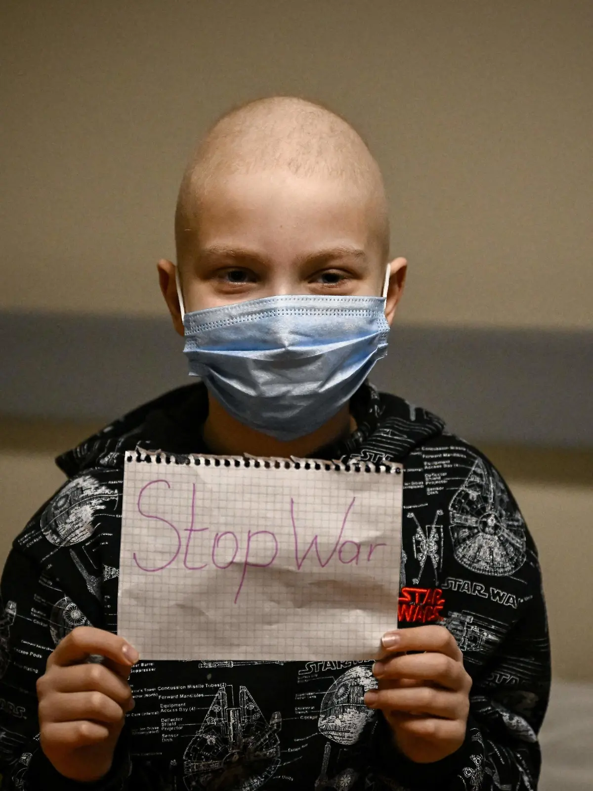 A child struggling with cancer holds a sign that says "Stop War" in the bomb shelter of an oncology center in Kyiv on February 28, 2022. - The Russian army said Monday that Ukrainian civilians could "freely" leave the country's capital Kyiv and claimed its airforce dominated Ukraine's skies as its invasion entered a fifth day. (Photo by Aris Messinis / AFP) (Photo by ARIS MESSINIS/AFP via Getty Images)