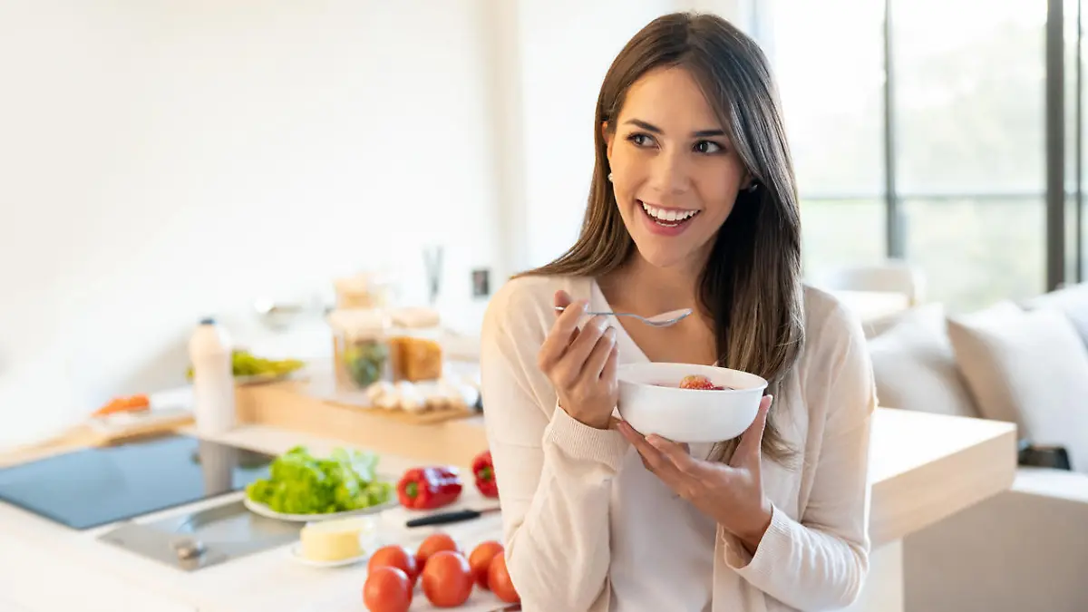 Portrait of a casual woman at home eating a healthy breakfast and looking happy - lifestyle concepts