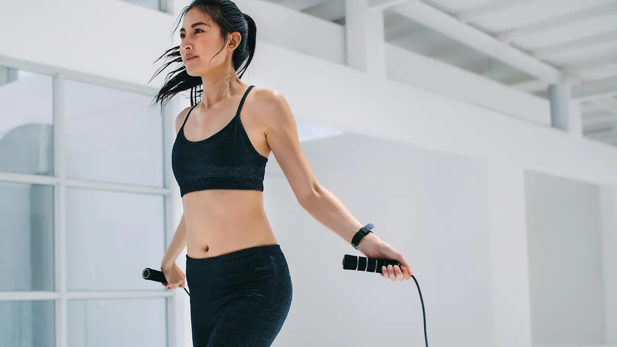 Female doing fitness training with jump ropes at health club. Fitness woman skipping ropes at gym.