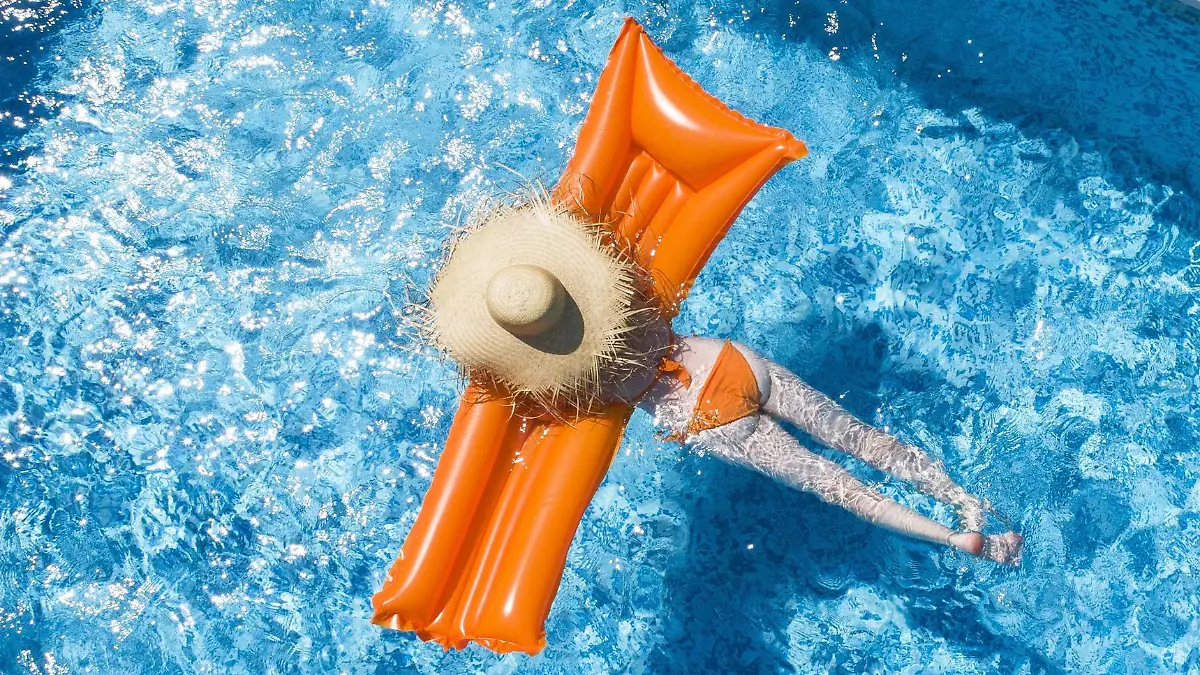 Back view of woman relaxing on orange airbed in swimming pool model released Symbolfoto property released PUBLICATIONxINxGERxSUIxAUTxHUNxONLY MAEF12347  