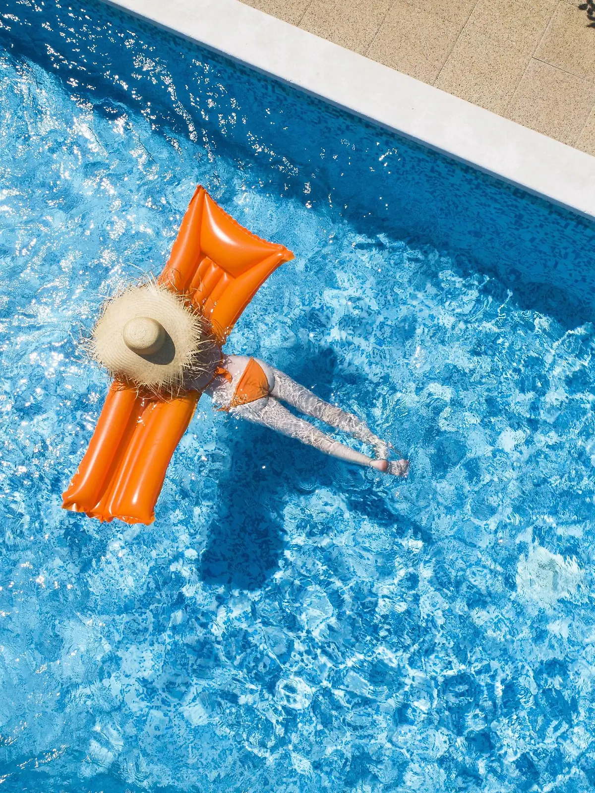 Back view of woman relaxing on orange airbed in swimming pool model released Symbolfoto property released PUBLICATIONxINxGERxSUIxAUTxHUNxONLY MAEF12347  