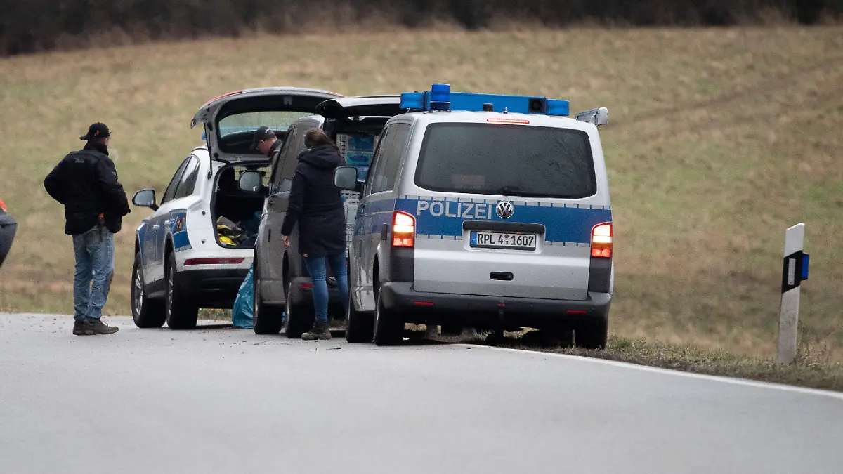 04.02.2022, Rheinland-Pfalz, Ulmet: Polizeiwagen und Beamte stehen an dem Tatort, an dem zwei Polizeibeamte bei einer Verkehrskontrolle erschossen wurden. Um 10 Uhr fand eine Gedenkfeier für die beiden Polizeibeamten in Kusel statt. Foto: Sebastian Gollnow/dpa +++ dpa-Bildfunk +++