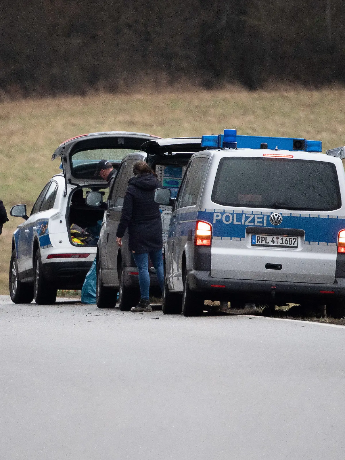 04.02.2022, Rheinland-Pfalz, Ulmet: Polizeiwagen und Beamte stehen an dem Tatort, an dem zwei Polizeibeamte bei einer Verkehrskontrolle erschossen wurden. Um 10 Uhr fand eine Gedenkfeier für die beiden Polizeibeamten in Kusel statt. Foto: Sebastian Gollnow/dpa +++ dpa-Bildfunk +++