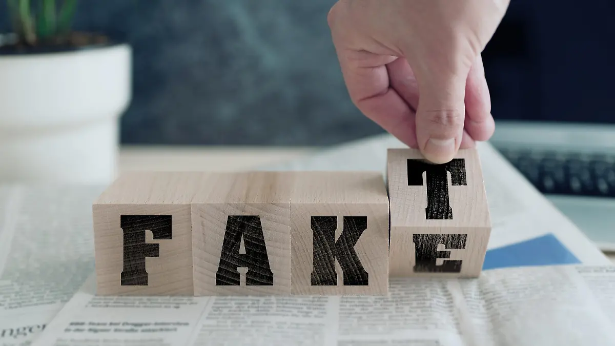 FAKE or FAKT, German for fact, on wooden blocks on newspaper, real news or fake news concept