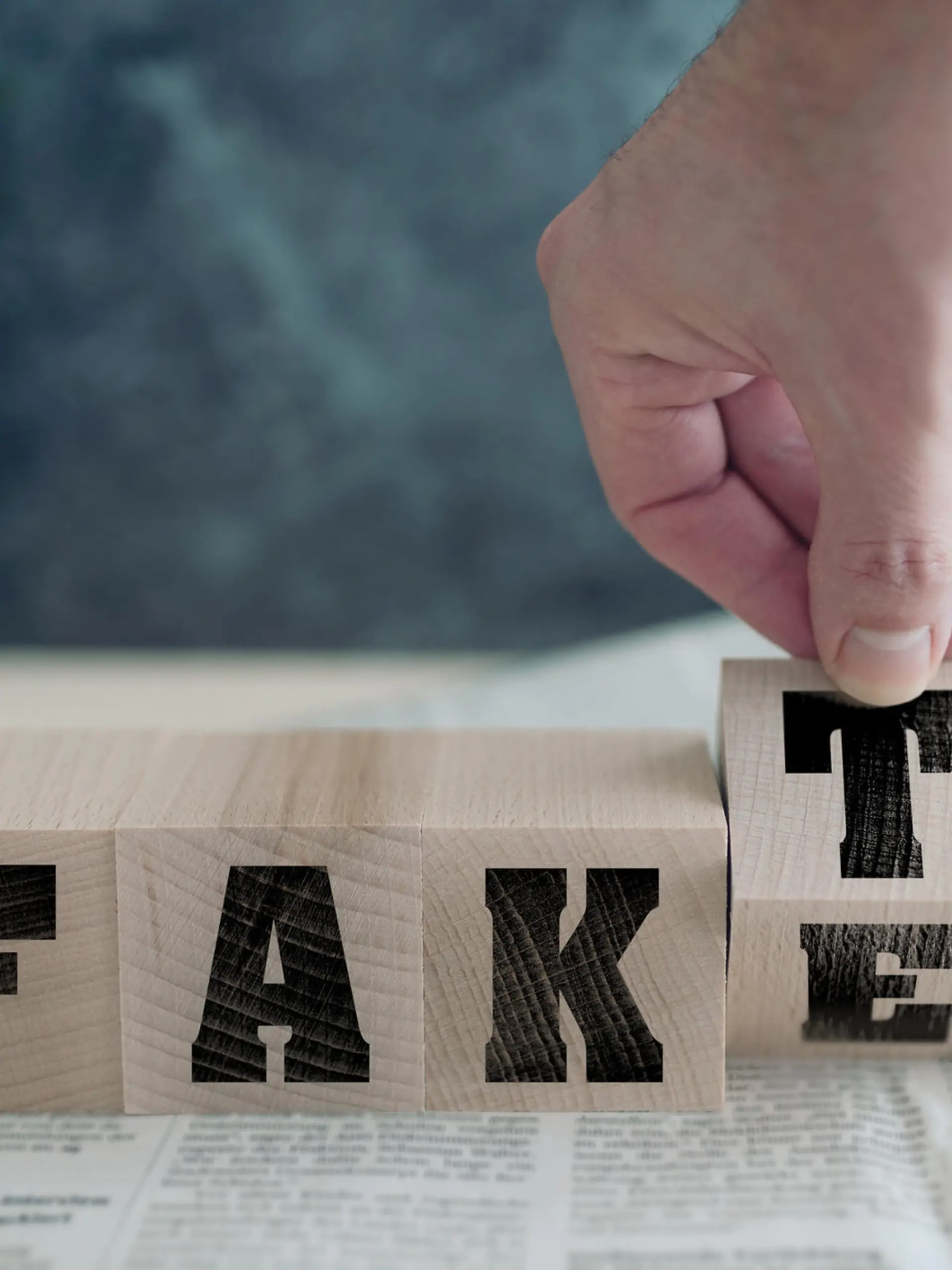 FAKE or FAKT, German for fact, on wooden blocks on newspaper, real news or fake news concept