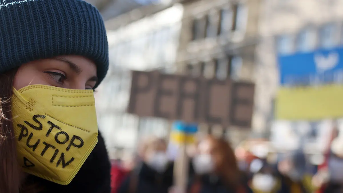 28.02.2022, Nordrhein-Westfalen, Köln: Eine Teilnehmerin der Friedensdemonstration am Rosenmontag trägt eine gelbe FFP2-Maske mit der Aufschrift "Stop Putin". Nach dem russischen Angriff auf die Ukraine wurde das Rosenmontagsfest abgesagt, stattdessen zieht ein Protestmarsch durch die Innenstadt - vorbei an vielen der Motivwagen, die eigentlich für den Rosenmontagszug gebaut worden waren. Foto: Oliver Berg/dpa +++ dpa-Bildfunk +++