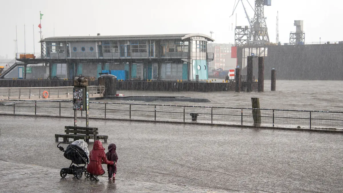 17.02.2022, Hamburg: Eine Frau und ein Kind stehen am Nachmittag während einer Sturmflut beim Hochwasser der Elbe am überschwemmten Fischmarkt. Foto: Daniel Bockwoldt/dpa +++ dpa-Bildfunk +++