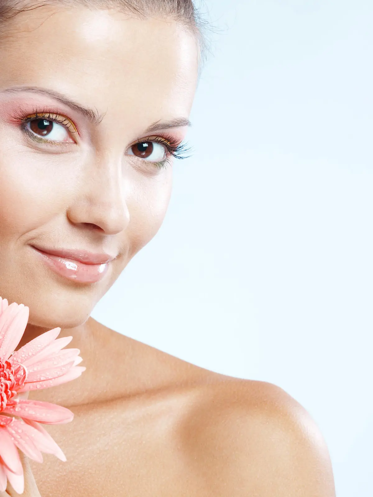 Beautiful female with fresh makeup and clear skin holding pink daisy over blue studio shot, Die schoene Frau mit dem frischen Make-Up und der reinen Haut, die rosa Gaensebluemchen ueber das blaue Studio haelt, schoss Keine Weitergabe an Drittverwerter.