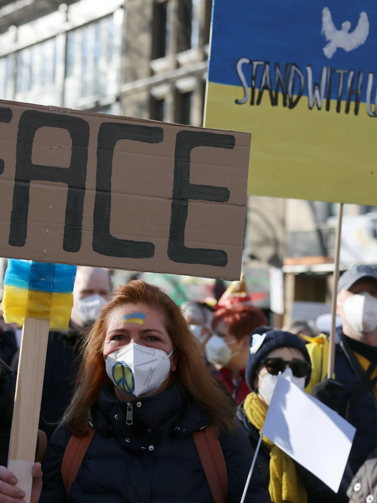 28.02.2022, Nordrhein-Westfalen, Köln: Teilnehmer der Friedensdemonstration am Rosenmontag halten Plakate mit der Aufschrift "Peace" und "Standwithukraine". Nach dem russischen Angriff auf die Ukraine wurde das Rosenmontagsfest abgesagt, stattdessen zieht ein Protestmarsch durch die Innenstadt - vorbei an vielen der Motivwagen, die eigentlich für den Rosenmontagszug gebaut worden waren. Foto: Oliver Berg/dpa +++ dpa-Bildfunk +++