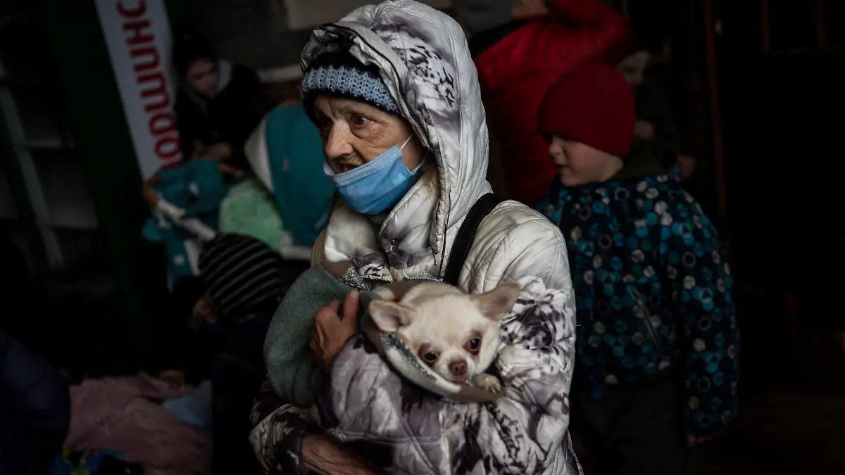 An elderly woman and her pet wait for a train inside Lviv railway station, Monday, Feb. 28, 2022, in Lviv, west Ukraine. Russia's military assault on Ukraine has entered its fifth day, forcing hundreds of thousands of Ukrainians and foreign residents to escape from war and seek refuge in neighboring countries. (AP Photo/Bernat Armangue)