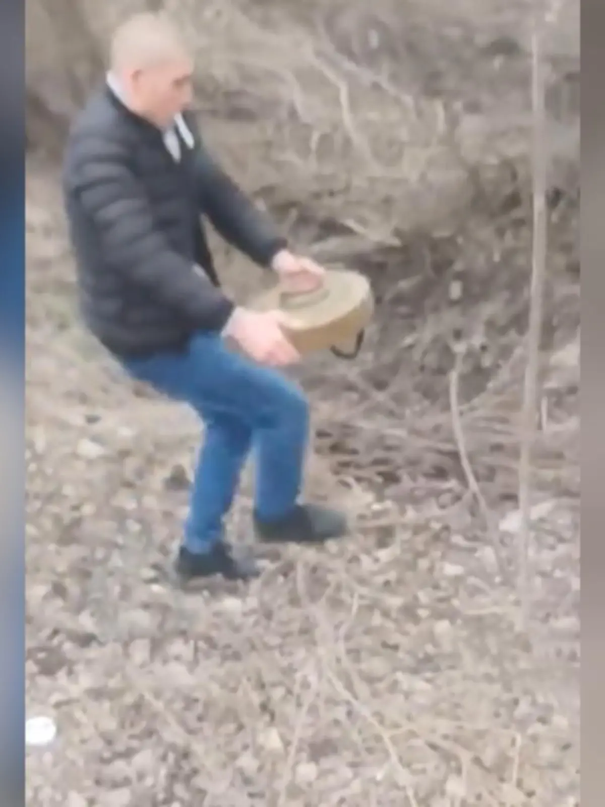 Mit bloßen Händen trägt dieser mutige Ukrainer eine Panzerabwehrmine von der Straße. Lässig mit einer Zigarette im Mund aber sichtlich angespannt riskiert er hier sein Leben. Der furchtlose Unbekannte hat die Mine an einem Straßenrand in Berdjansk gefunden und sie in ein Waldstück gebracht.