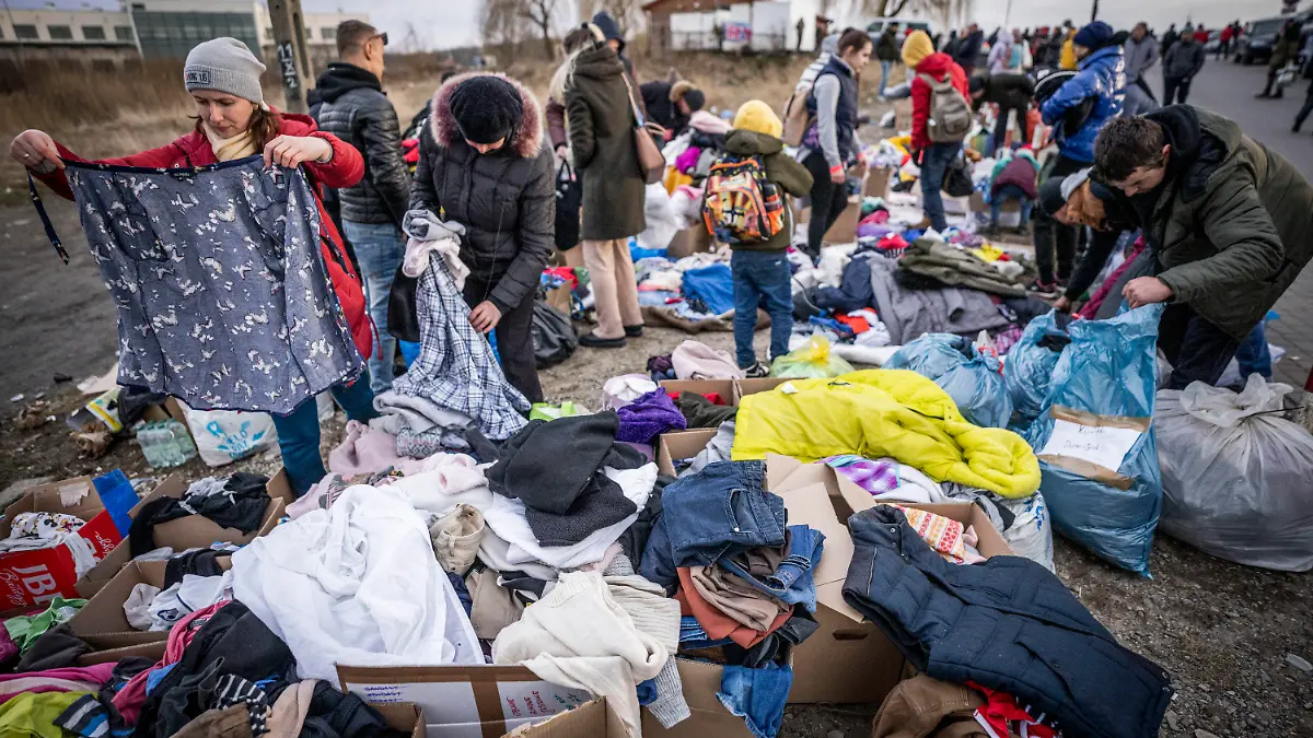 26.02.2022, Polen, Przemysl: Geflüchtete aus der Ukraine suchen nach ihrem Grenzübertritt von Schehyni in der Ukraine nach Medyka in Polen im polnischen Grenzgebiet nach passender Kleidung, die von polnischen Bürgern bereitgestellt wurde. Zahlreiche Menschen verlassen nach dem Angriff Russlands auf die Ukraine das Land. Viele flüchten nach Polen. Foto: Michael Kappeler/dpa +++ dpa-Bildfunk +++