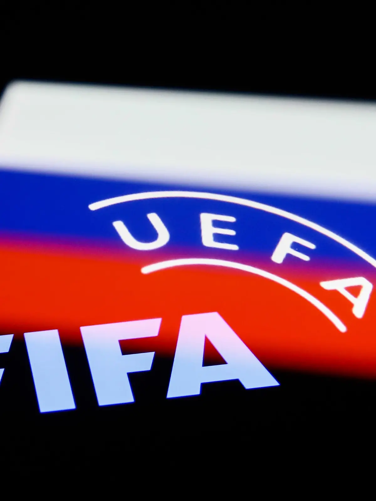 FIFA and UEFA logos displayed on phone screens and Russian flag displayed on a phone screen are seen in this multiple exposure illustration photo taken in Krakow, Poland on February 28, 2022. (Photo illustration by Jakub Porzycki/NurPhoto)