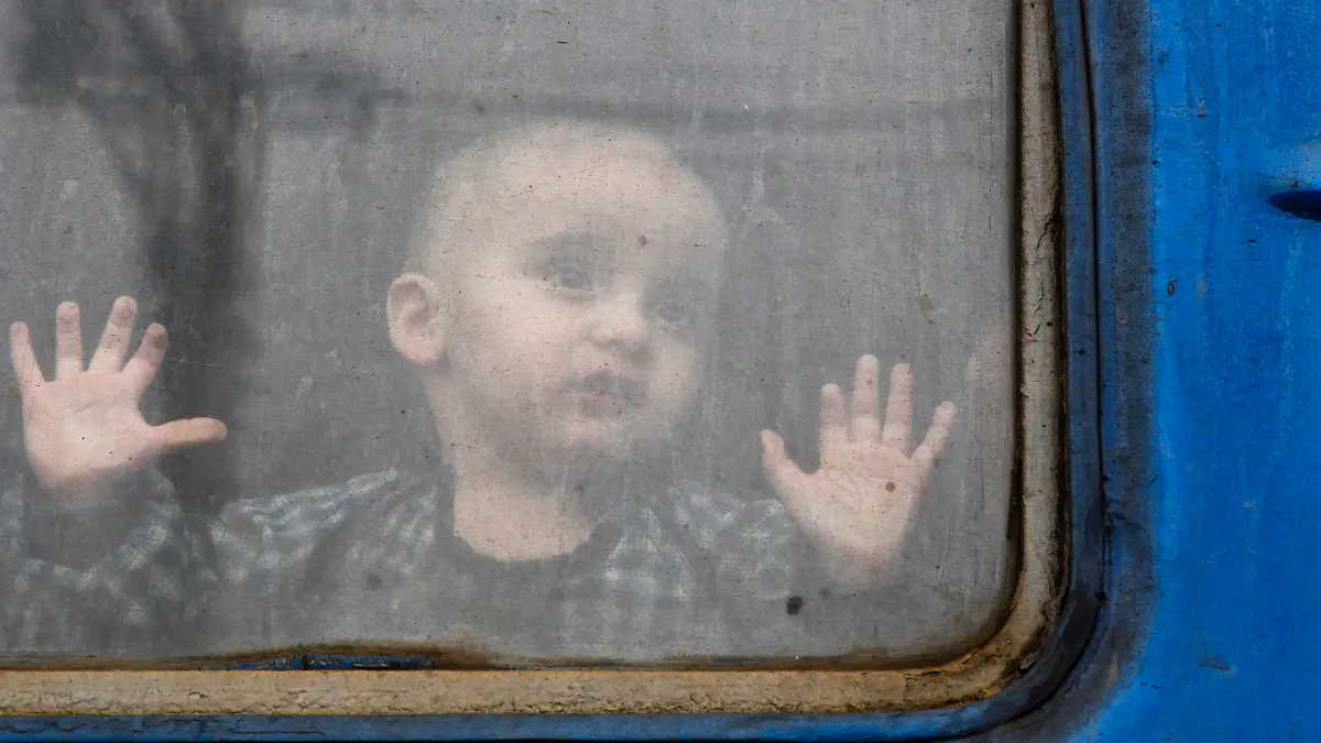 27.02.2022, Ukraine, Kramatorsk: Ein Kind beobachtet auf dem Bahnhof von Kramatorsk einen Zug, der darauf wartet, die Ukraine zu verlassen. Wegen des russischen Angriffs auf die Ukraine sind nach Angaben des UN-Flüchtlingshilfswerks (UNHCR) etwa 368 000 Menschen auf der Flucht. Foto: Andriy Andriyenko/AP/dpa +++ dpa-Bildfunk +++