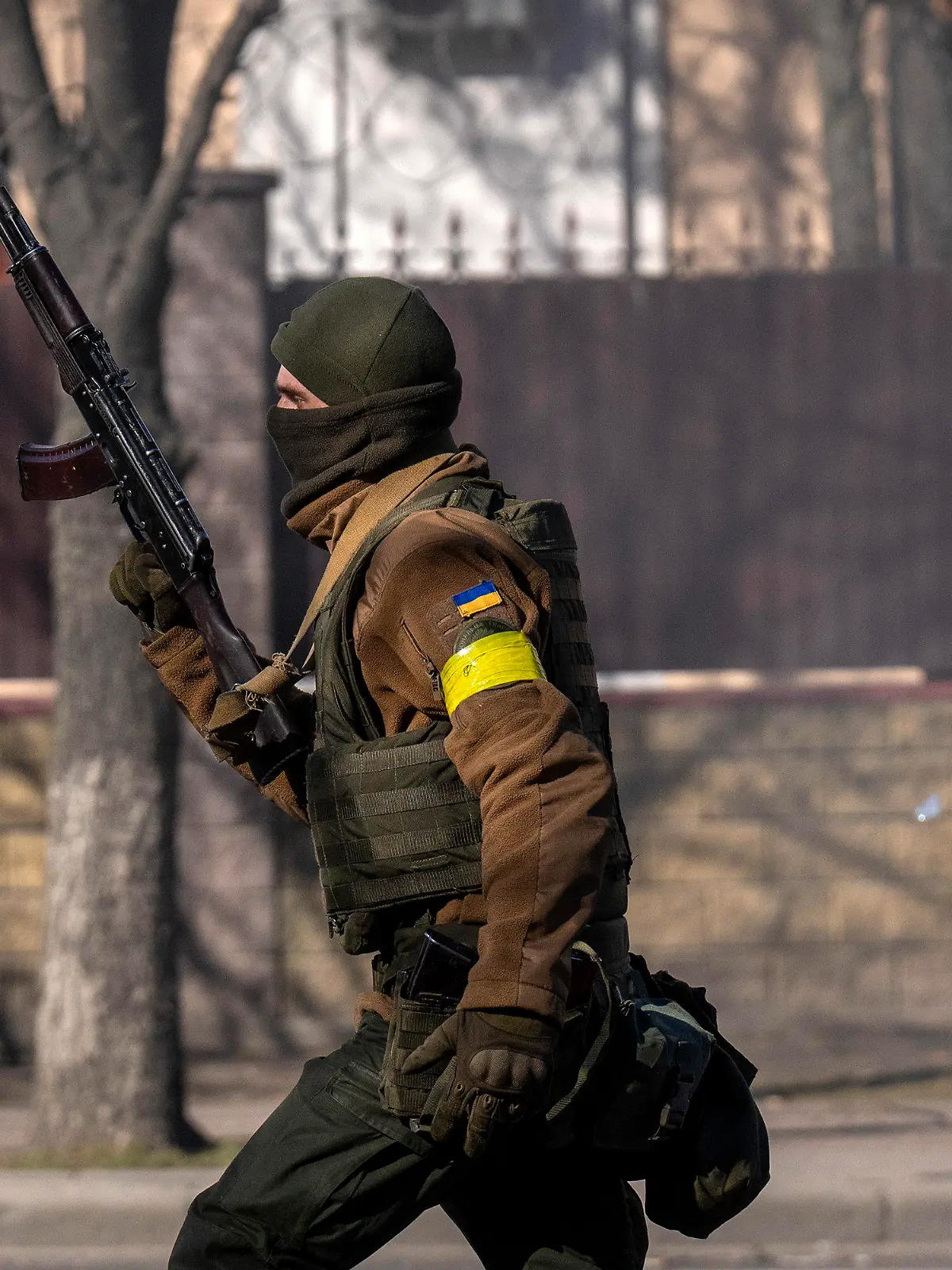 26.02.2022, Ukraine, Kiew: Ein ukrainischer Soldat geht mit seiner Waffe in der Hand vor einer Militäreinrichtung. Russische Truppen haben den erwarteten Angriff auf die Ukraine gestartet und drangen in die Hauptstadt vor. Foto: Emilio Morenatti/AP/dpa +++ dpa-Bildfunk +++