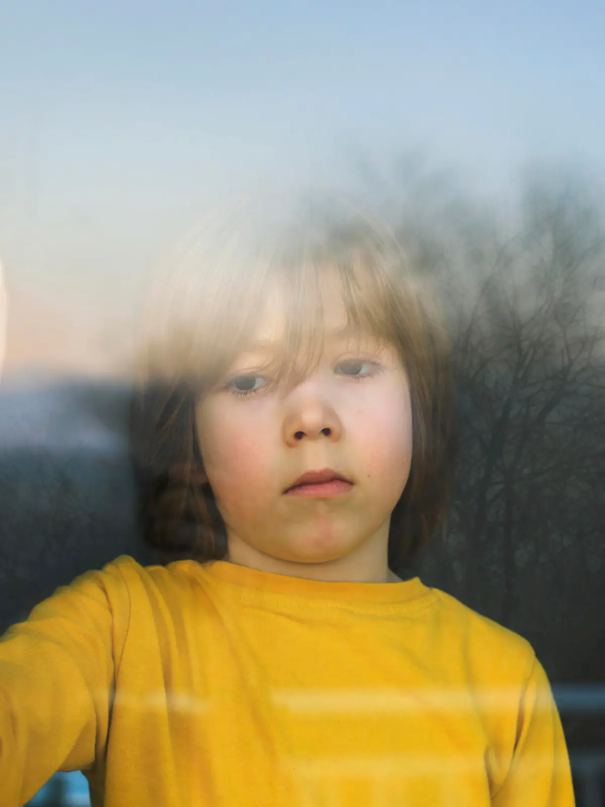 Kind steht traurig am Fenster