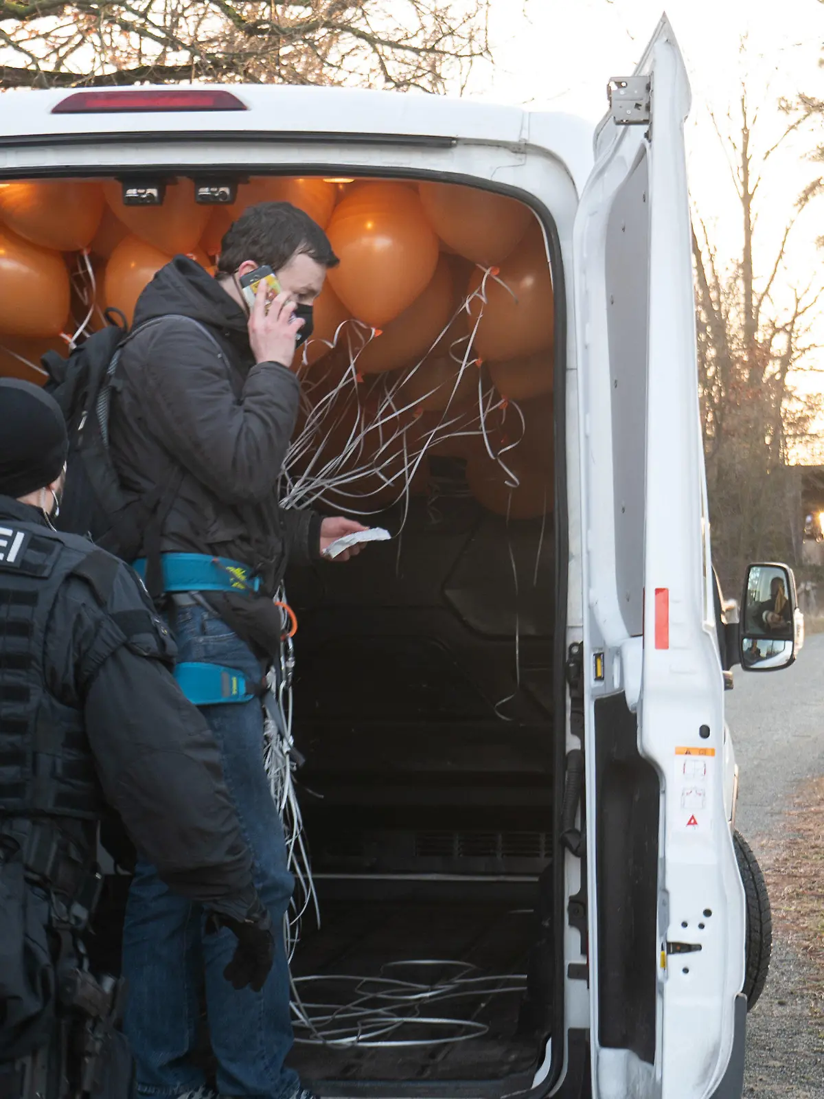 25.02.2022, Hessen, Kelsterbach: Ein Polizeibeamter schließt einen Transporter mit Luftballons, mit denen die Klimaaktivisten der Aktion ·Aufstand der letzten Generation· am Flughafen Frankfurt den Sicherheitsbereich betreten wollten. Die Polizei stoppte die Aktion noch am Transporter. Foto: Sebastian Gollnow/dpa +++ dpa-Bildfunk +++