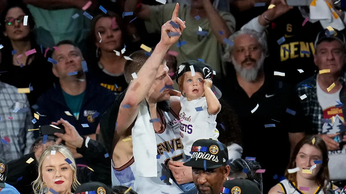 Denver Nuggets center Nikola Jokic, center, celebrates with his daughter after the team won the NBA Championship with a victory over the Miami Heat in Game 5 of basketball's NBA Finals, Monday, June 12, 2023, in Denver. (AP Photo/David Zalubowski)