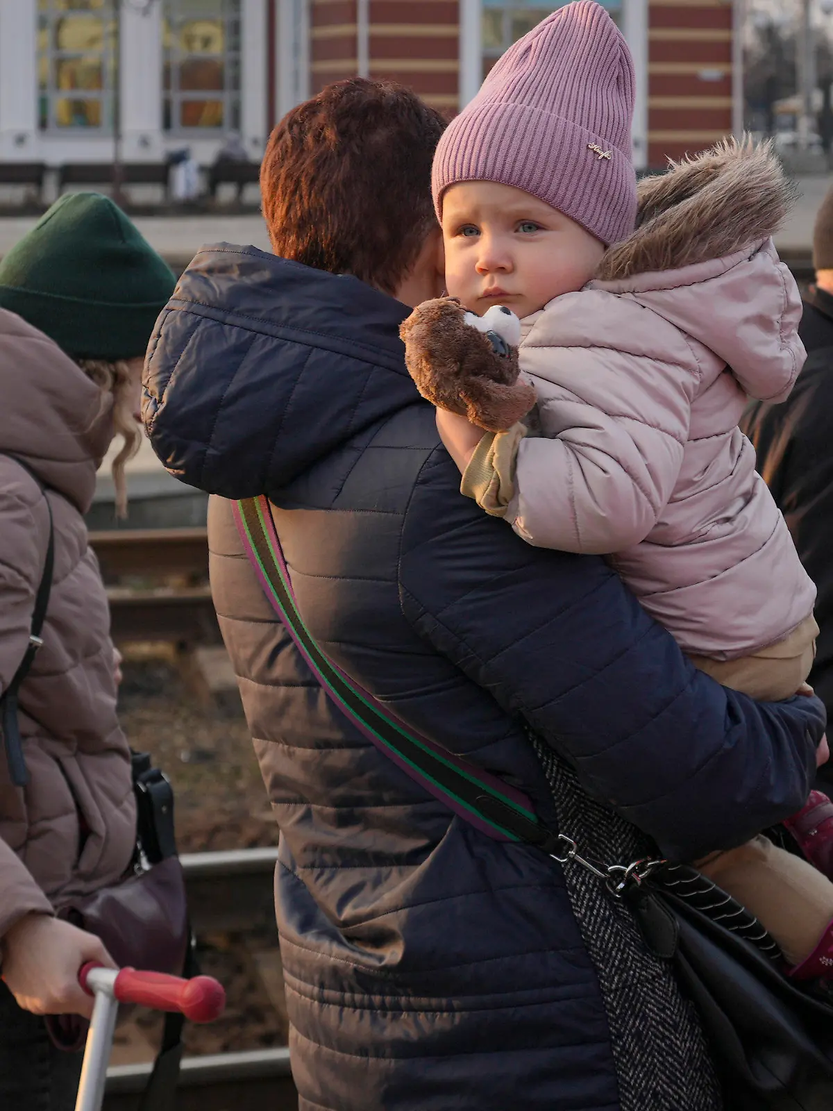 24.02.2022, Ukraine, Kramatorsk: Eine Frau geht mit ihrem Kind im Arm einen Bahnsteig in Kramatorsk in der Region Donezk in der Ostukraine entlang, um einen Zug nach Kiew zu nehmen. Russische Truppen haben ihren erwarteten Angriff auf die Ukraine gestartet. Foto: Vadim Ghirda/AP/dpa +++ dpa-Bildfunk +++