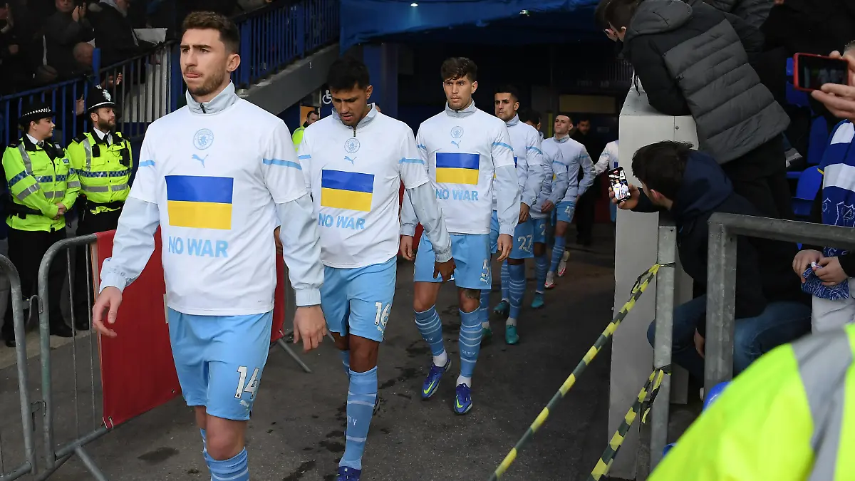 LIVERPOOL, ENGLAND - FEBRUARY 26: Aymeric Laporte of Manchester City leads their team out with Ukrainian flags on their jackets to indicate peace and sympathy with Ukraine prior to the Premier League match between Everton and Manchester City at Goodison Park on February 26, 2022 in Liverpool, England. (Photo by Michael Regan/Getty Images)
