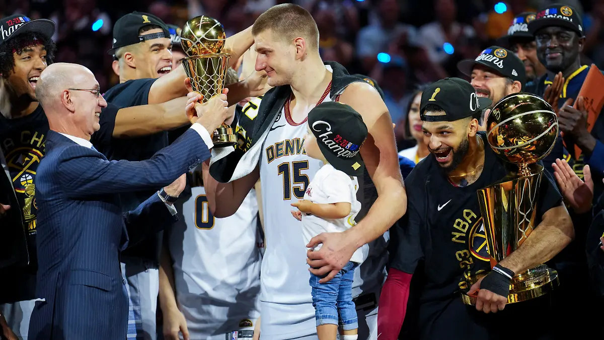 12.06.2023, USA, Denver: Basketball: NBA, Play-off-Runde, Finale, Denver Nuggets - Miami Heat, 5. Spieltag: Commissioner Adam Silver (l) überreicht den MVP-Preis an Denver Nuggets-Center Nikola Jokic (M), nachdem das Team die NBA-Meisterschaft gewonnen hat. Foto: Jack Dempsey/AP/dpa +++ dpa-Bildfunk +++