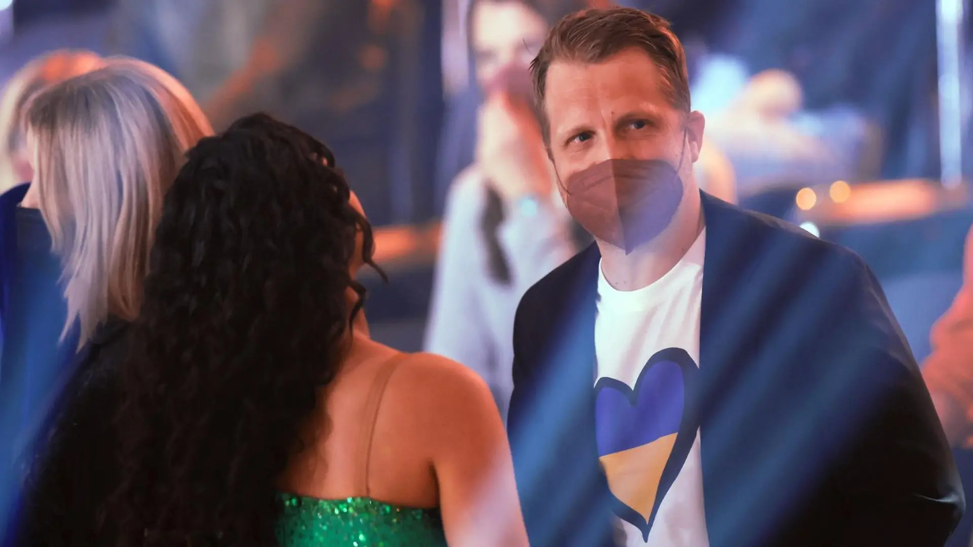 25.02.2022, Nordrhein-Westfalen, Köln: Oliver Pocher, Moderator, steht neben seiner Frau Amira mit einem T-Shirt, dass ein Herz in den Farben der ukrainischen Flagge zeigt, in der RTL-Tanzshow "Let's Dance" im Coloneum. Foto: Rolf Vennenbernd/dpa +++ dpa-Bildfunk +++