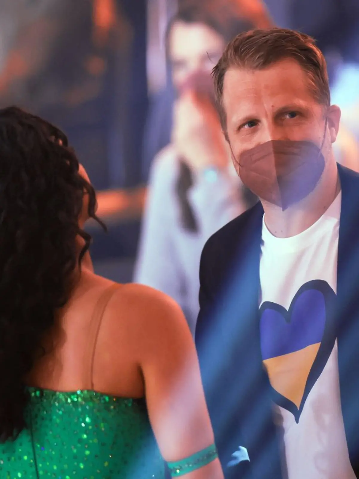 25.02.2022, Nordrhein-Westfalen, Köln: Oliver Pocher, Moderator, steht neben seiner Frau Amira mit einem T-Shirt, dass ein Herz in den Farben der ukrainischen Flagge zeigt, in der RTL-Tanzshow "Let's Dance" im Coloneum. Foto: Rolf Vennenbernd/dpa +++ dpa-Bildfunk +++