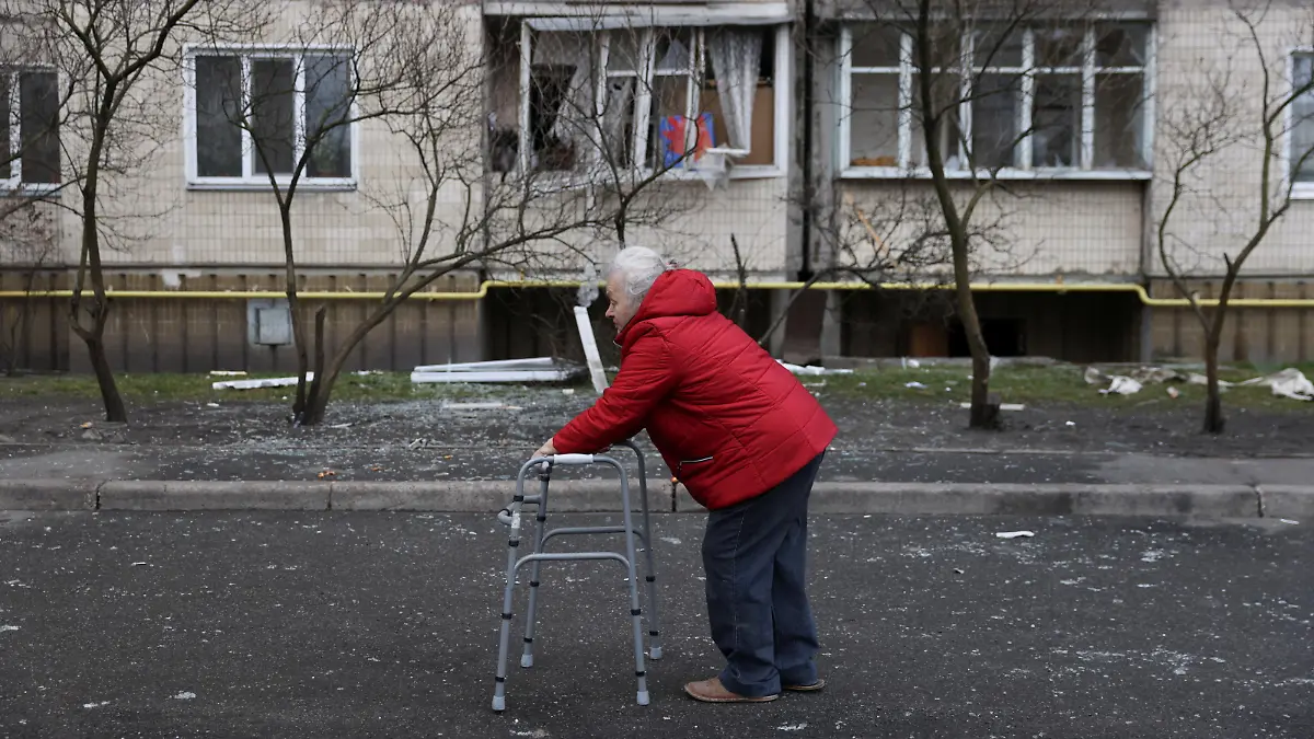 A woman with a walker passes in front of a damaged residential building, after Russia launched a massive military operation against Ukraine, in Kyiv, Ukraine February 25, 2022. REUTERS/Umit Bektas
