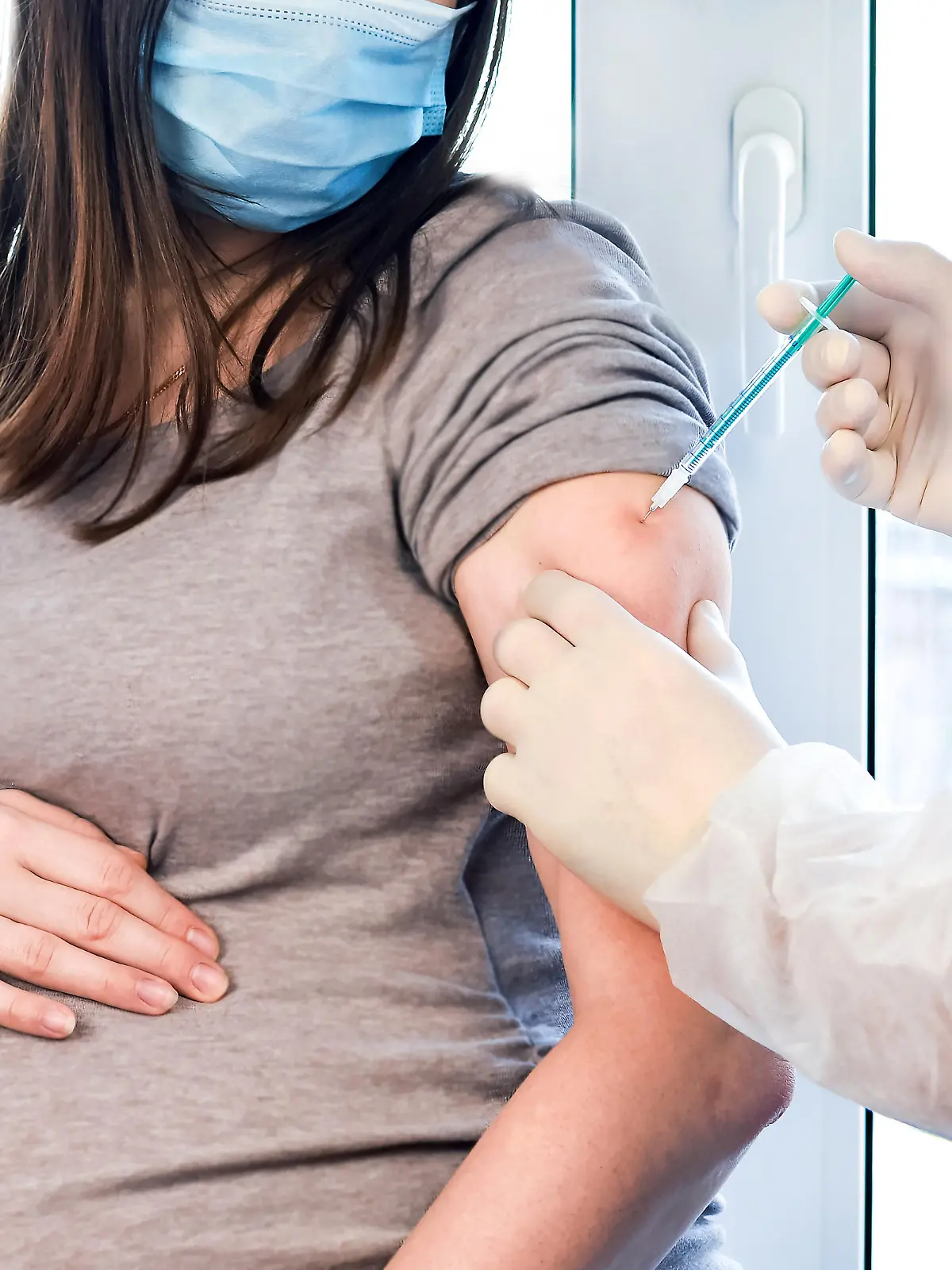 Pregnant Vaccination. Pregnant Woman In Face Mask Getting Vaccinated in Clinic. Doctor Giving Corona Virus Vaccine Injection Patient. Covid-19 Flu Protection.